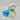 White fluffy dog wearing a blue dress with star pattern on a gray background